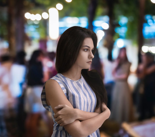 Young woman standing away from a noisy crowd
