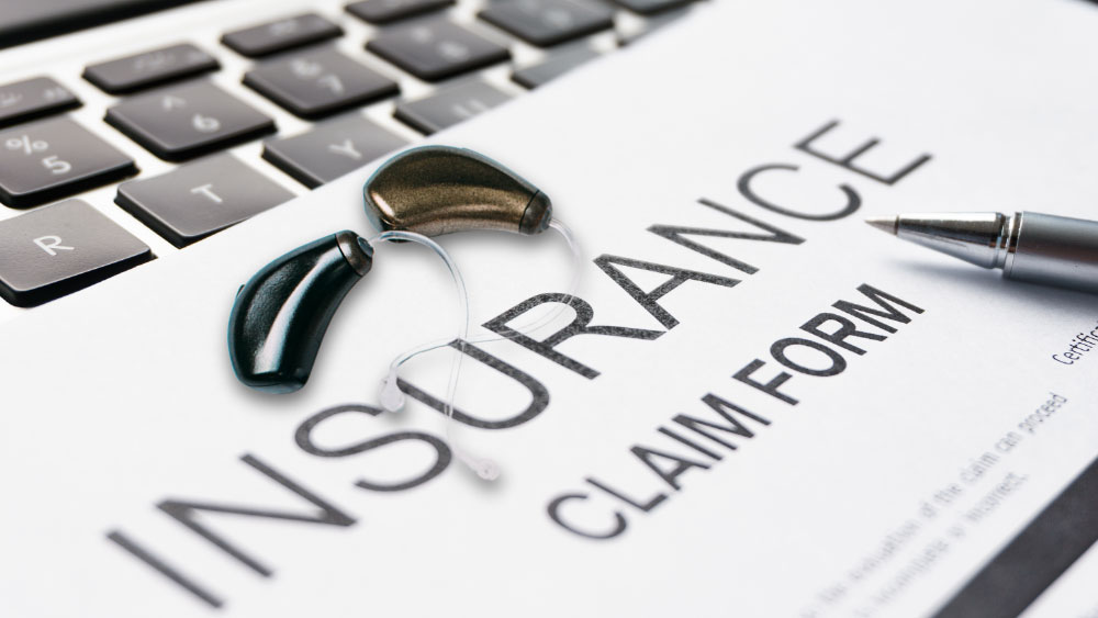 Insurance papers with a pair of hearing aids lying on top.