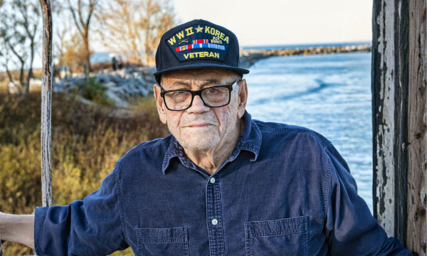 A old Korean war veteran looking calm outdoors with a lake in the background