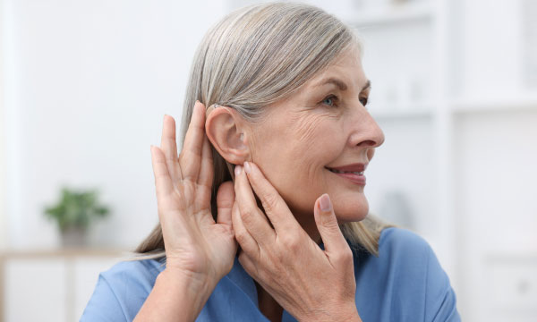 Senior woman putting on her hearing aid