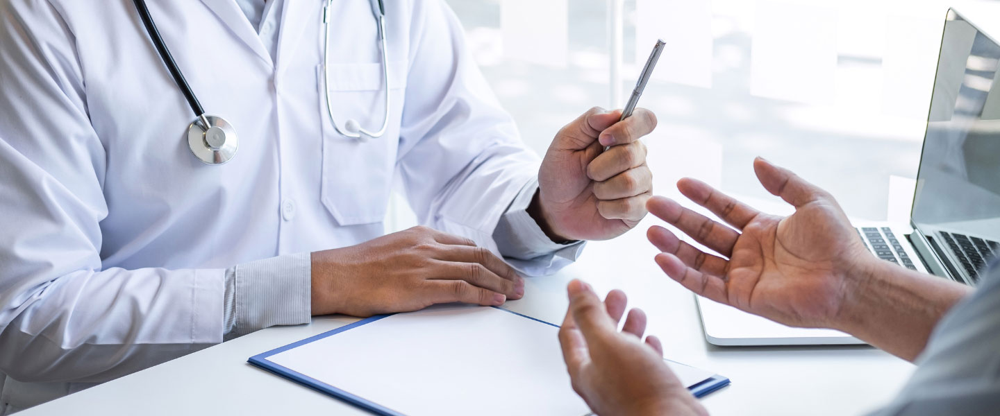 Closeup of patient talking to doctor at their desk.