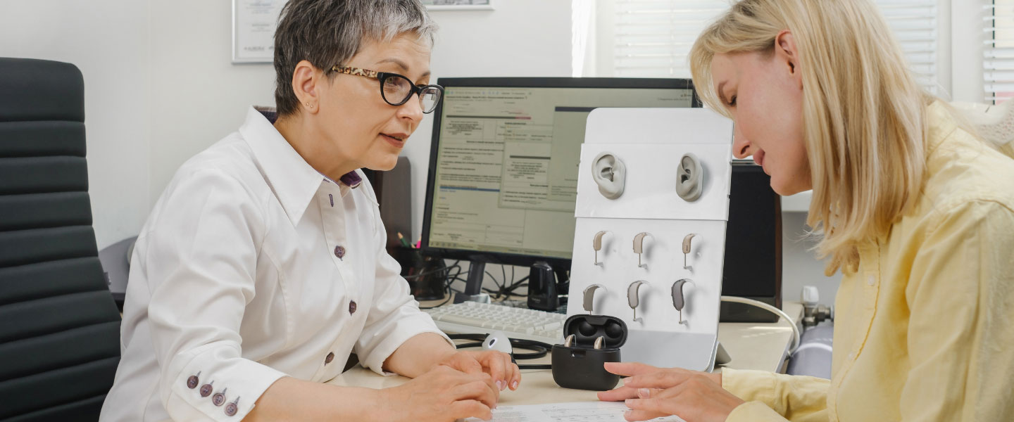 Audiologist showing a woman new hearing aid models