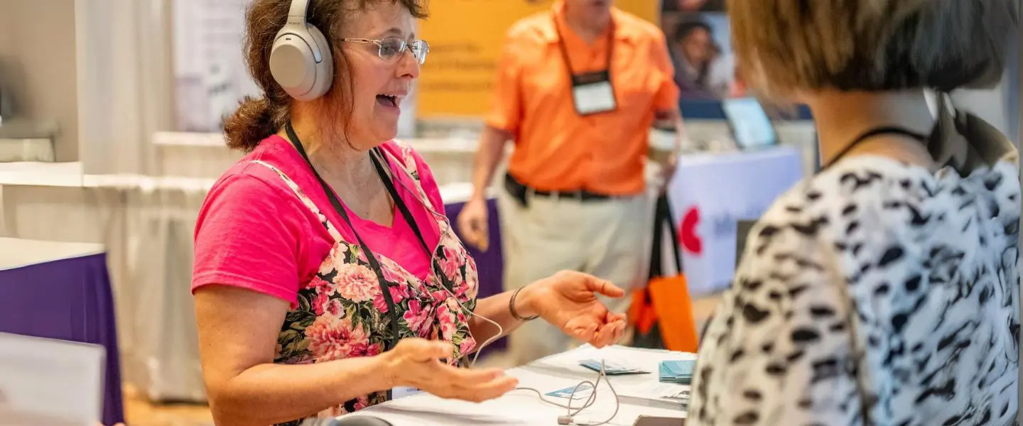 A woman wearing headphones trying assistive listening devices