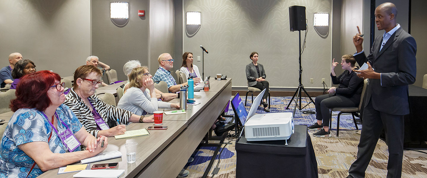 An in-person audience listening at a convention workshop event