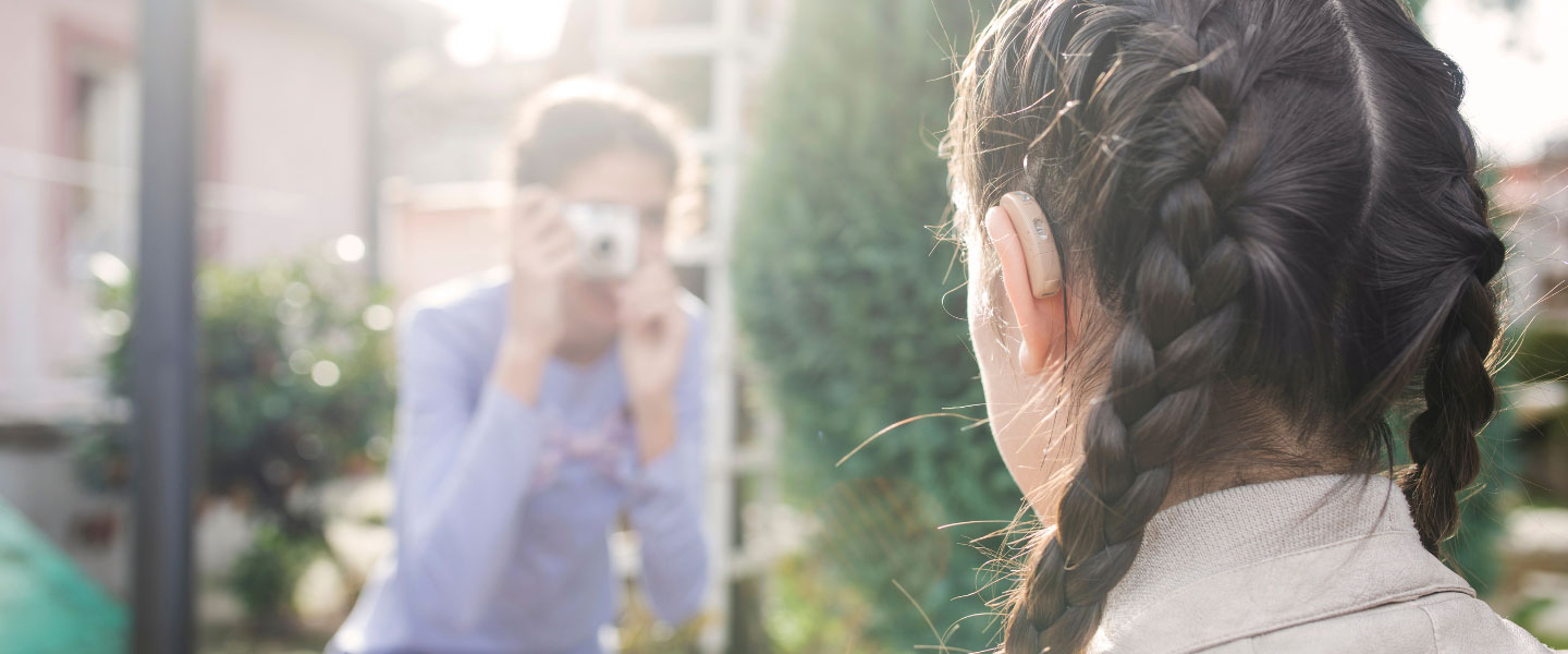 A young girl with a hearing aid getting her picture taken.