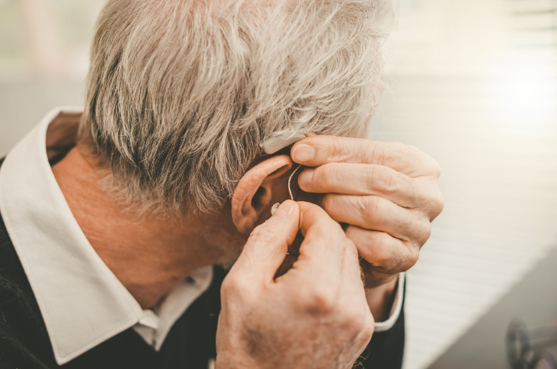 Older man putting on his hearing aid