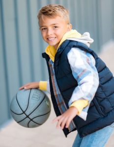 Young boy smiling while dribbling a basketball