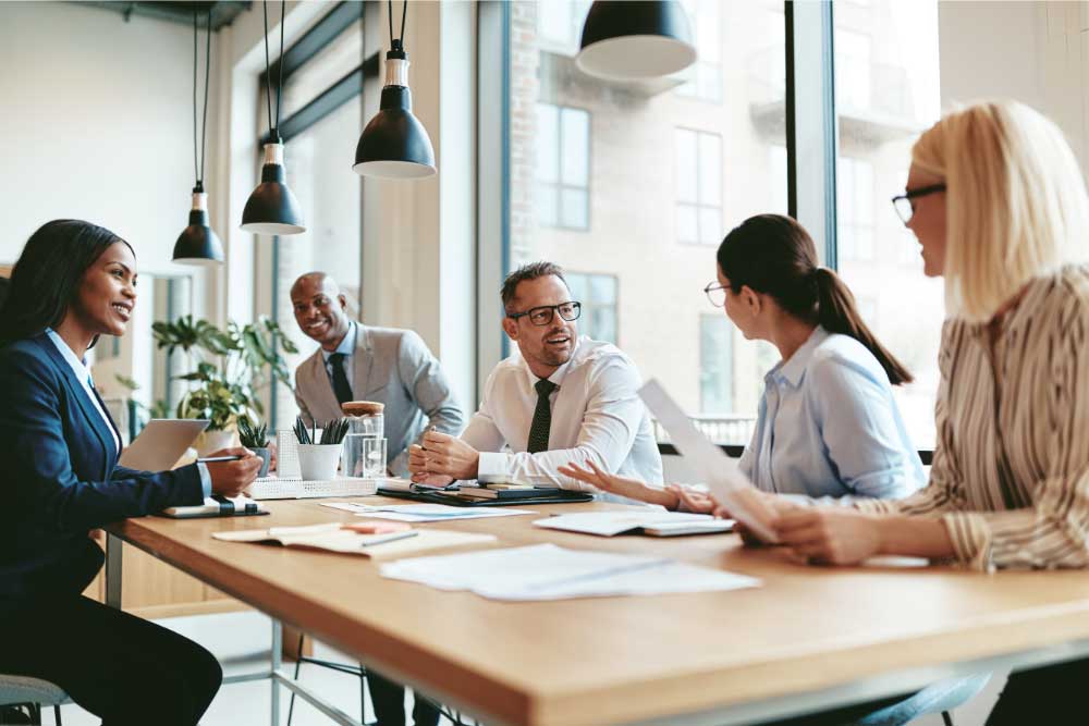 Group of workers in a workplace setting discussion meeting details.