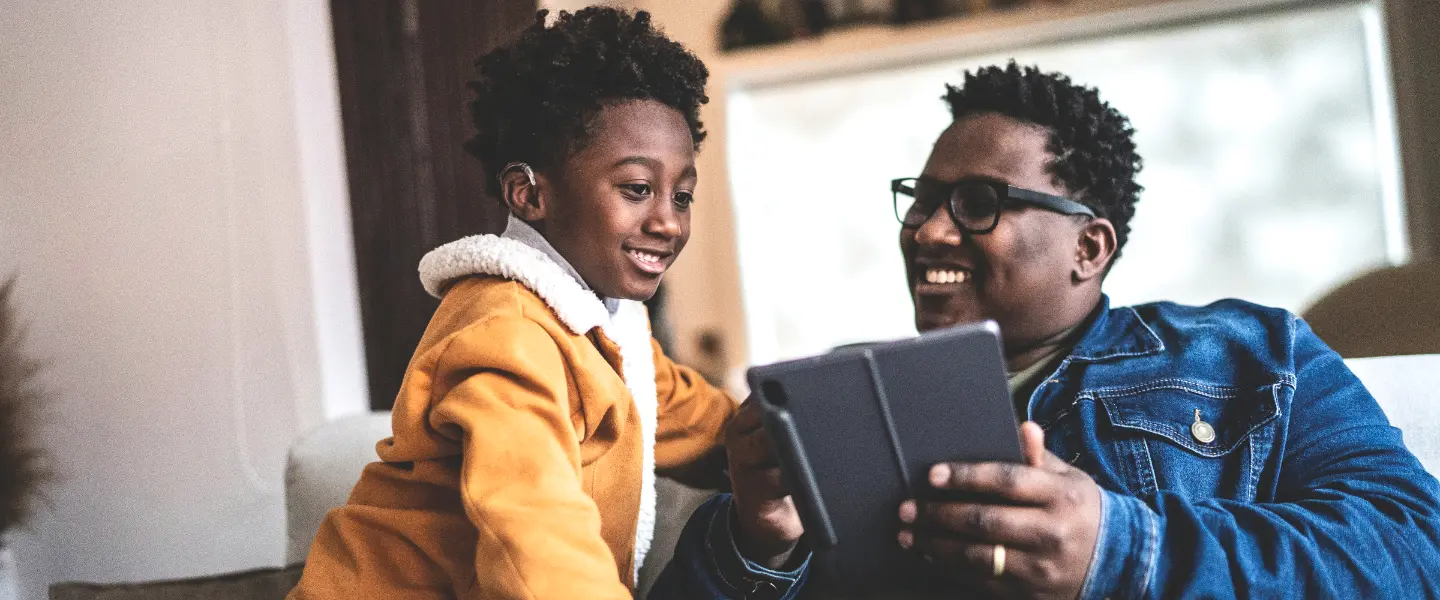 A father enjoying his time with his son sharing information from his tablet.