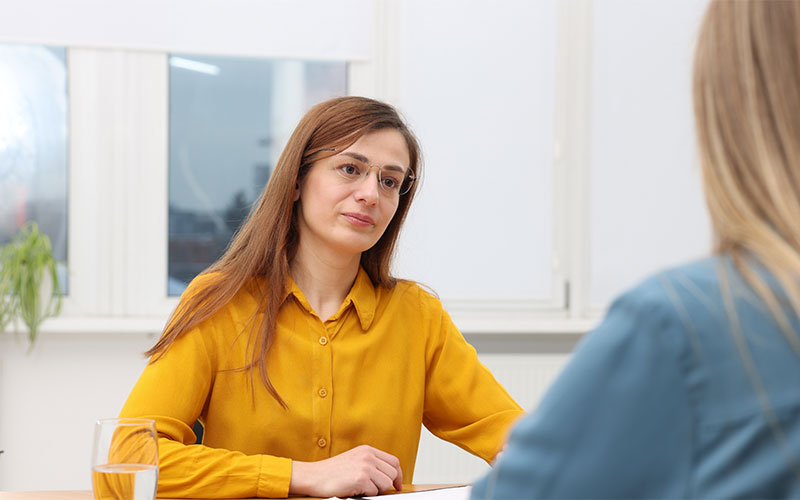 Two women in an office setting having a private conversation.