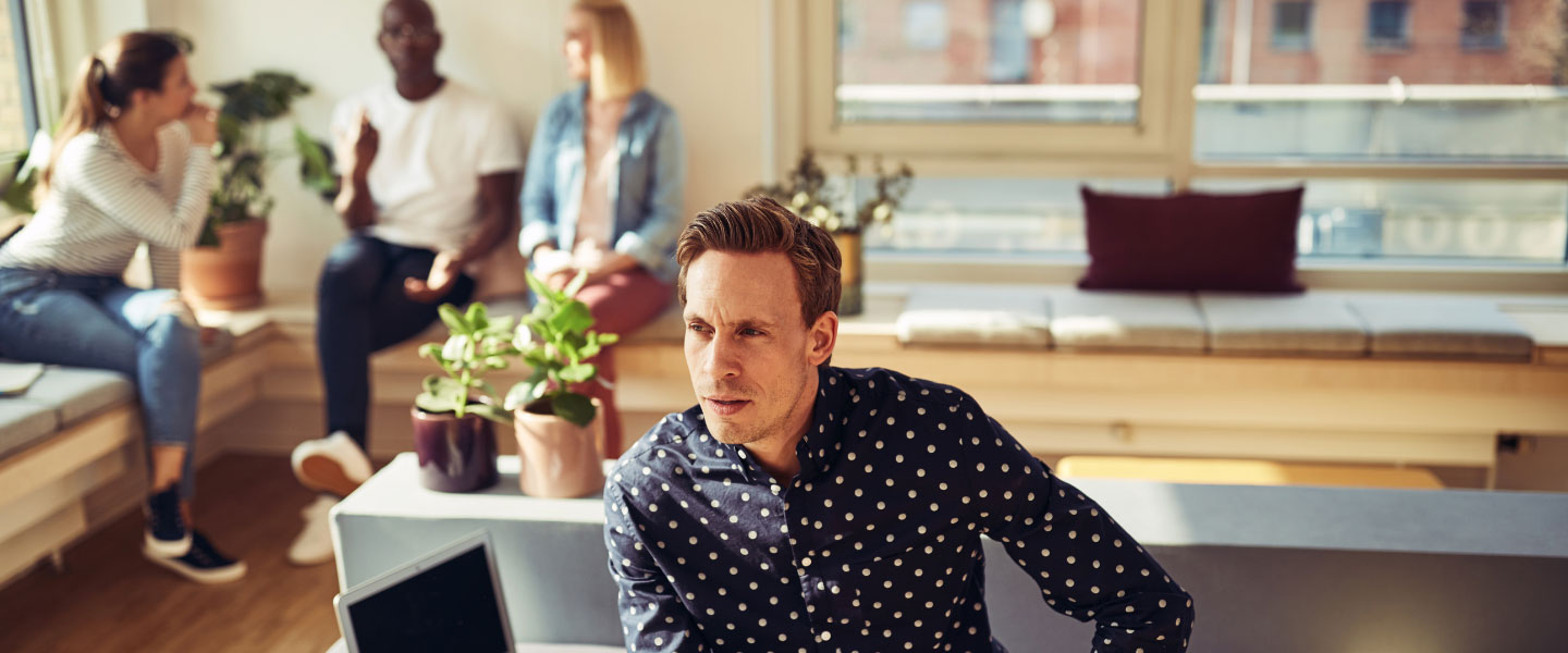 A middle age man looking in the distance while employees talk behind him